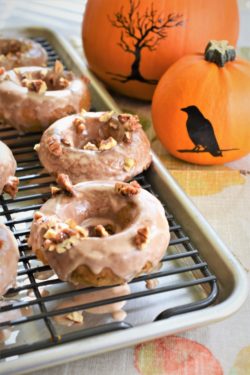 Vegan Pumpkin Pecan Donuts on cooling rack with spooky pumpkins 