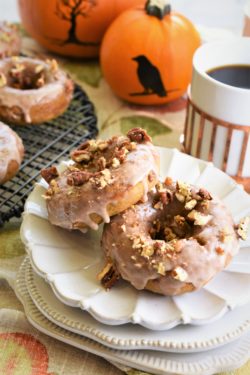 two stacked pumpkin donuts on a stack of dessert plates