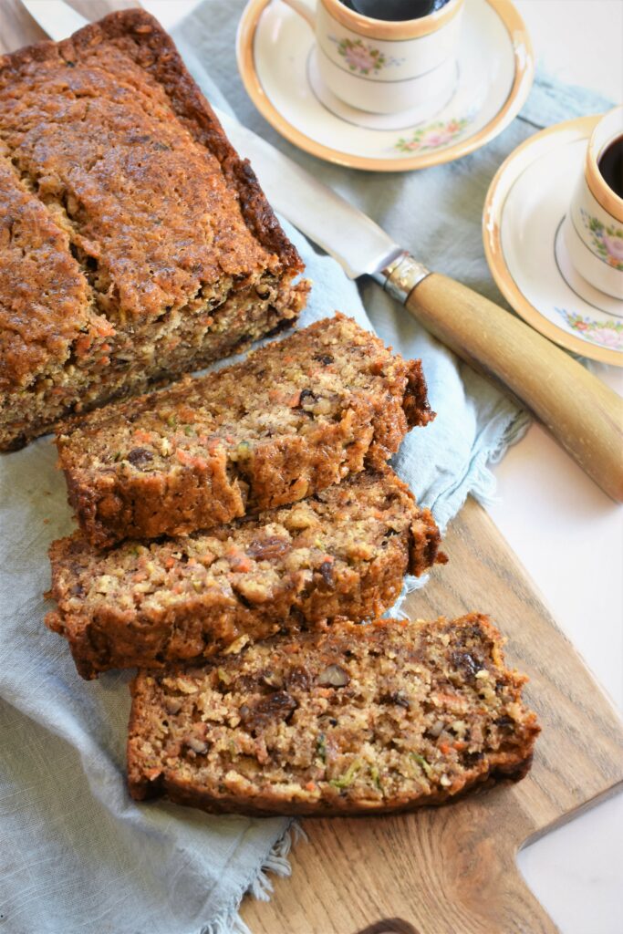 close up image of quick bread on cutting board with antique knife blue napkin and cups of coffee in the background