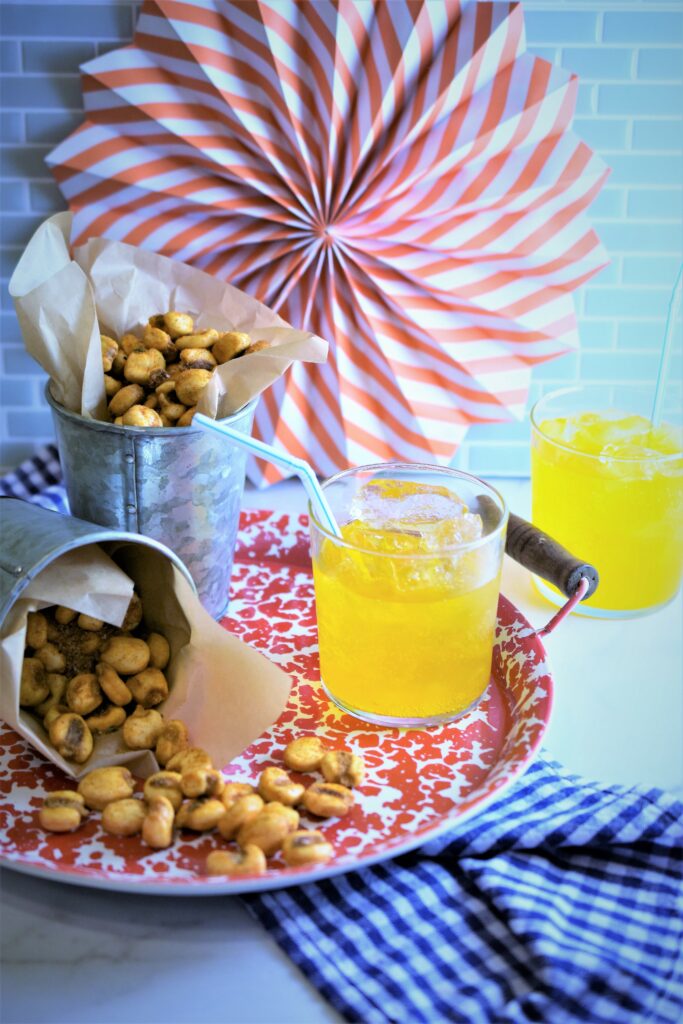 BBQ corn nuts in metal cups on red and white splatter tray with orange soda