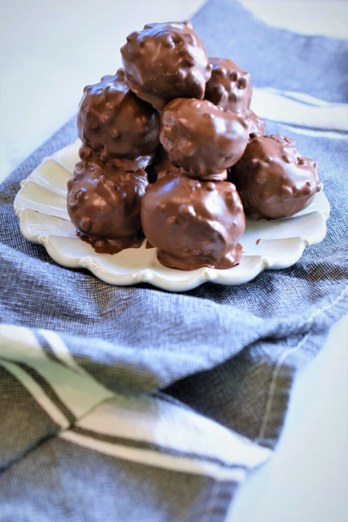 small white scalloped dessert plate with a stack of peanut butter s'more bombs on blue kitchen towel