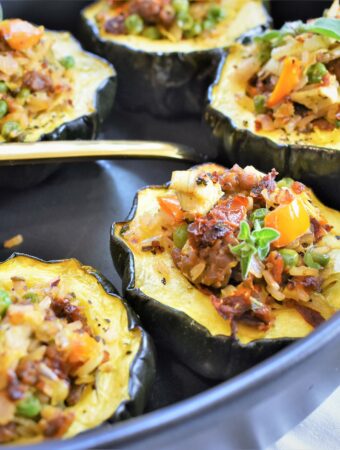 Beyond Italian style stuffed acorn squash with quinoa in black casserole dish with large gold serving spoon