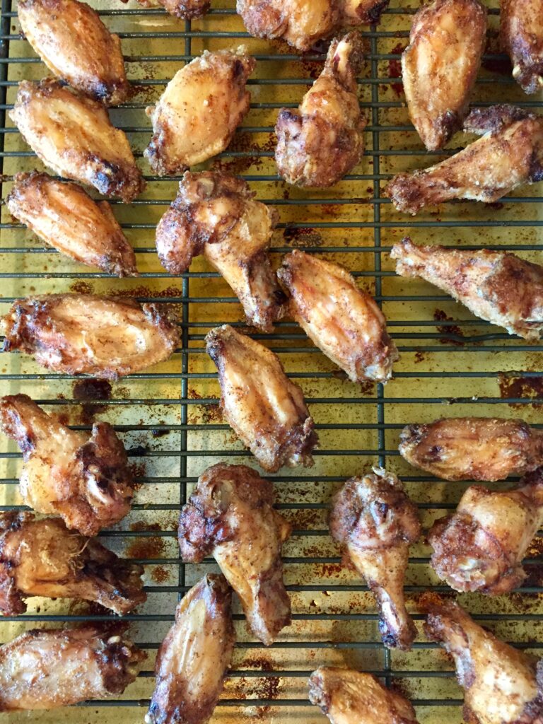 roasting rack on sheet pan with a couple of dozen just roasted chicken wings