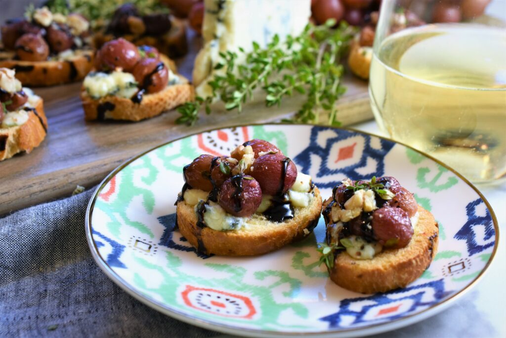 appetizer plate with two servings of bruschetta with a glass of white wine off to the side