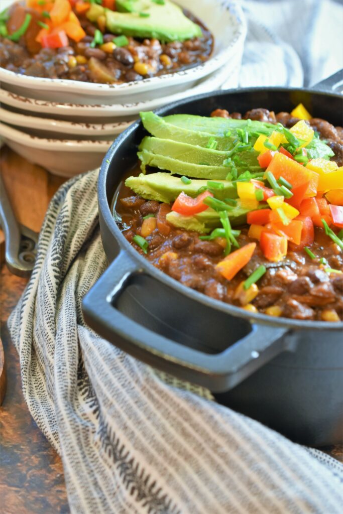 serving pot with bowls of hearty vegan black bean chipotle chili with coffee & cocoa