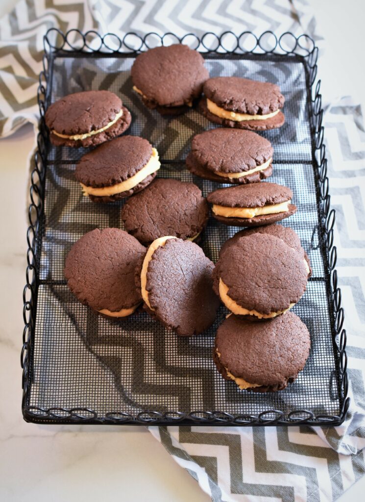 Vegan Chocolate Peanut Butter Sandwich Cookies on black vintage wire cooling rack on gray and white chevron print napkin