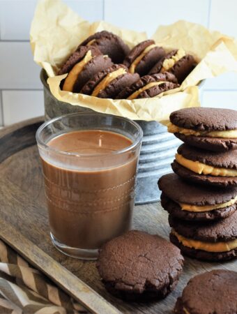 wood tray with vegan chocolate peanut butter sandwich cookies and chocolate almond milk