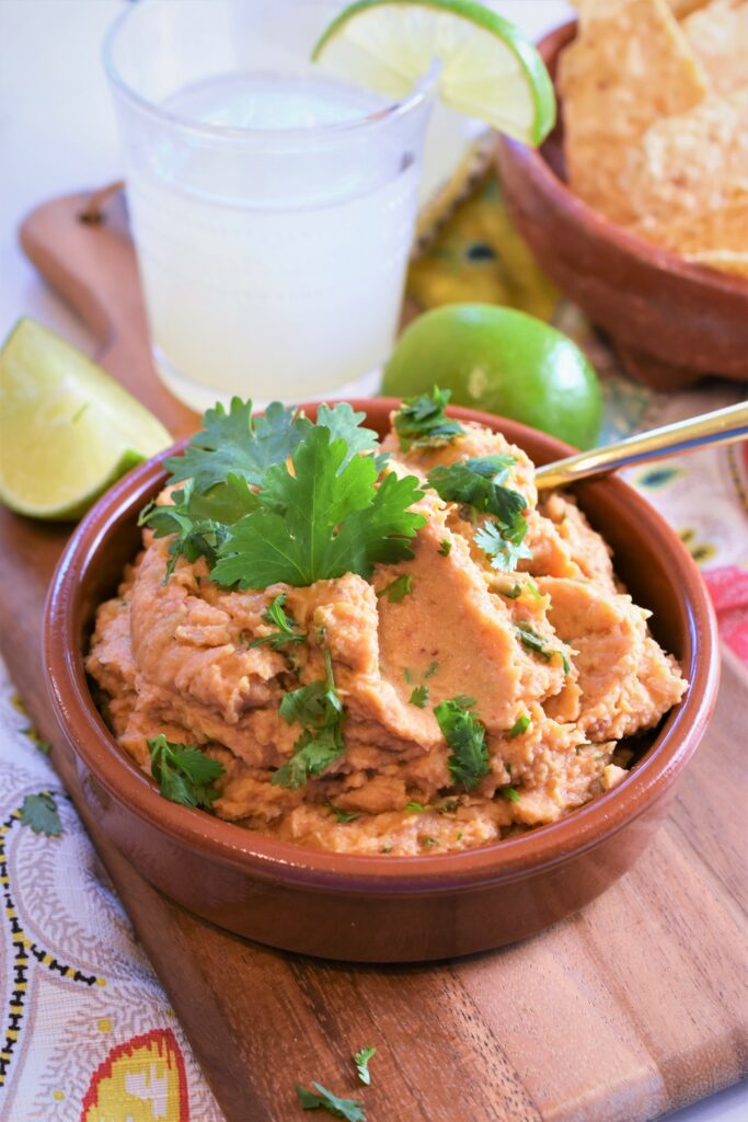 up close view of clay bowl of chipotle white bean dip with limes off to the side