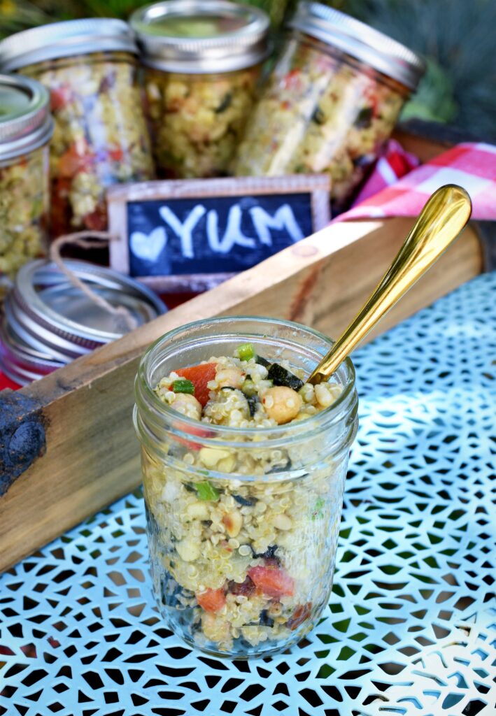 filled small mason jar of salad with gold fork in it