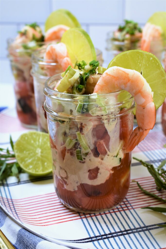 chipotle shrimp & watermelon cocktail in small canning jars on red white and blue plaid patterned tray garnished with lime