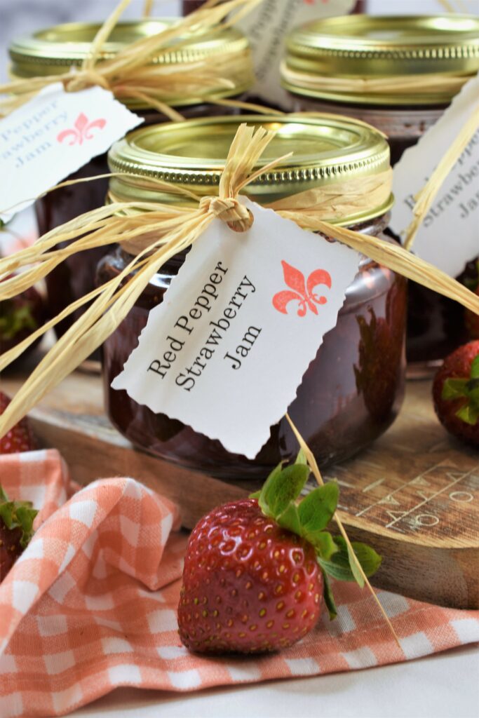 up close image of jar of red pepper strawberry jam with label tied around top of jar