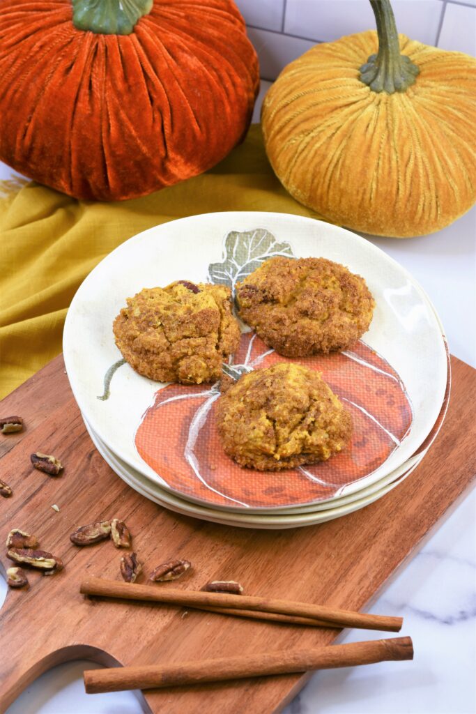 quick vegan pumpkin cookies on pumpkin patterned plate on cutting board with velvet pumpkins in the background
