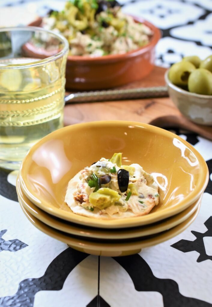 olive sun-dried tomato cream cheese spread on cracker in Dijon yellow tapas dishes