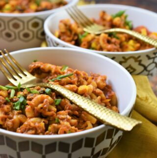 vegan chorizo Mexican goulash in 3 modern gold and white bowls with gold forks