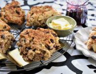 large image of breakfast apple scones on round wire cooling rack with dish of butter and jar of jam
