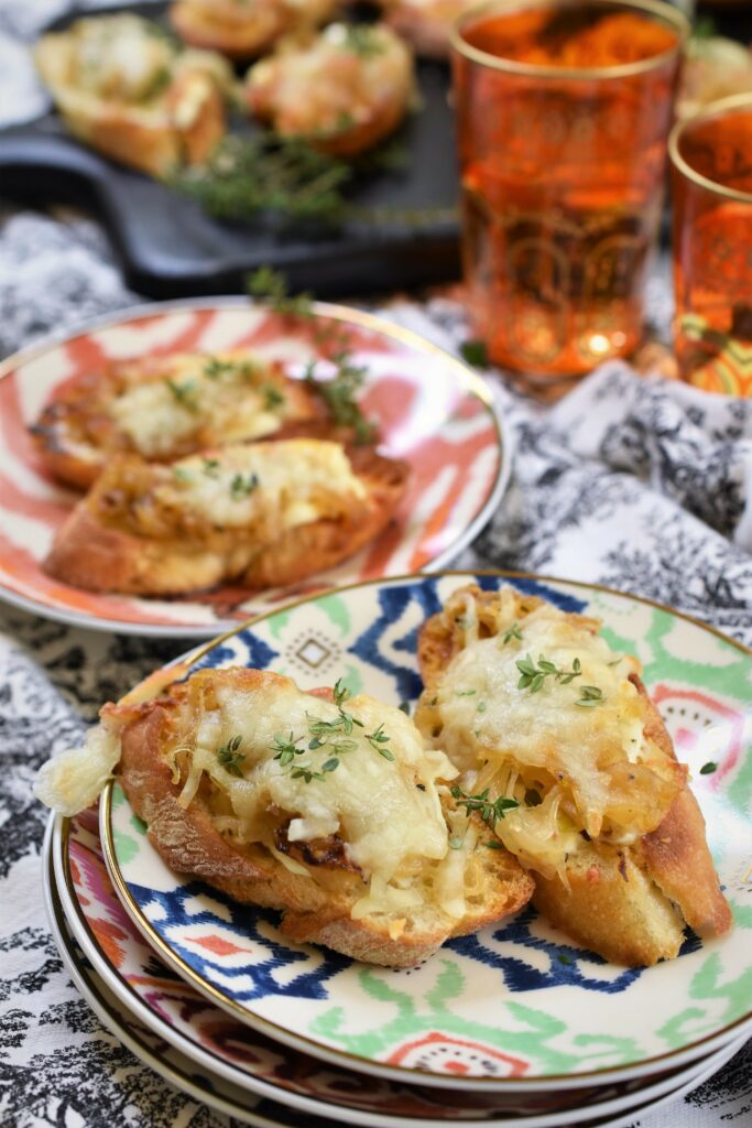 broiled cheese bruschetta on a stack of colorful appetizer plates