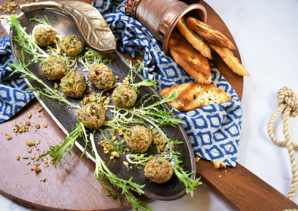 fig blue walnut truffles in dark metal dish with brass leaf with red wine in the background