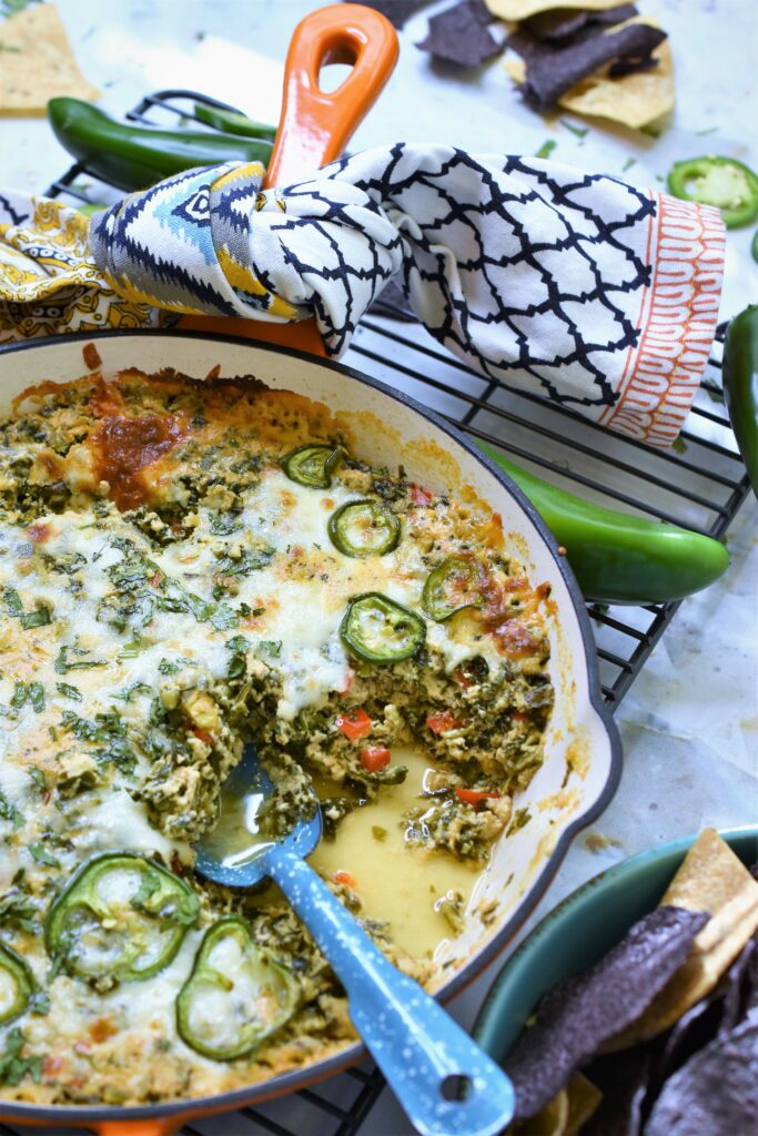 Baked Mexican Spinach Dip in orange skillet with blue spoon