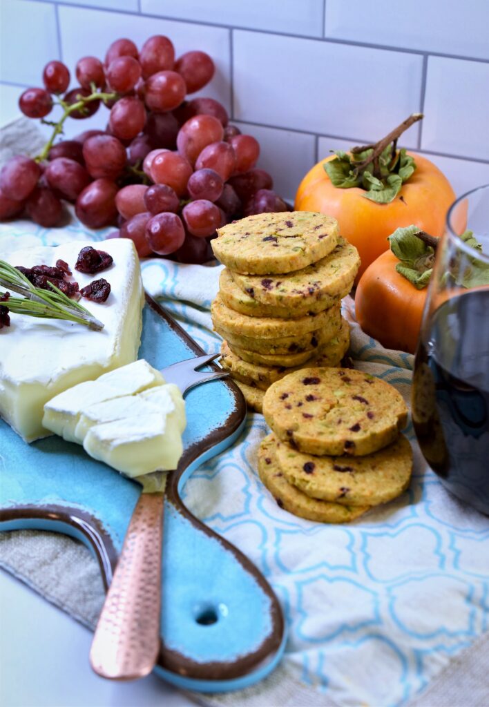 smoked gouda crackers with aqua cutting board and Brie with fresh grapes and persimmons