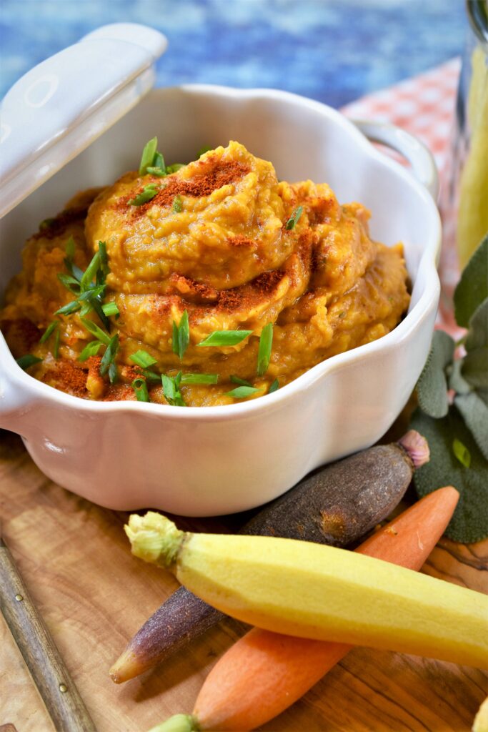 pumpkin white bean dip in ceramic bowl with fresh multi colored carrots