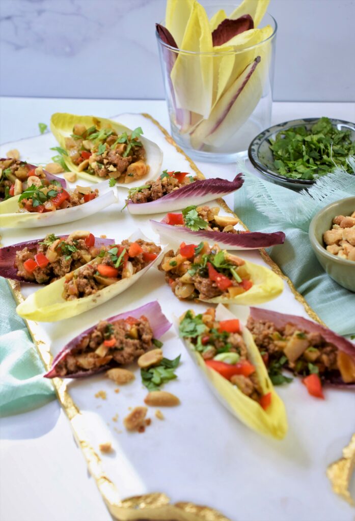 Asian appetizer on white marble cutting board surrounded by toppings