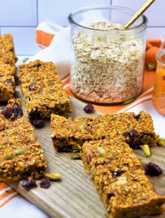 Fall oat bars with nuts and seeds on bread board with jar of oatmeal and jar of pumpkin puree