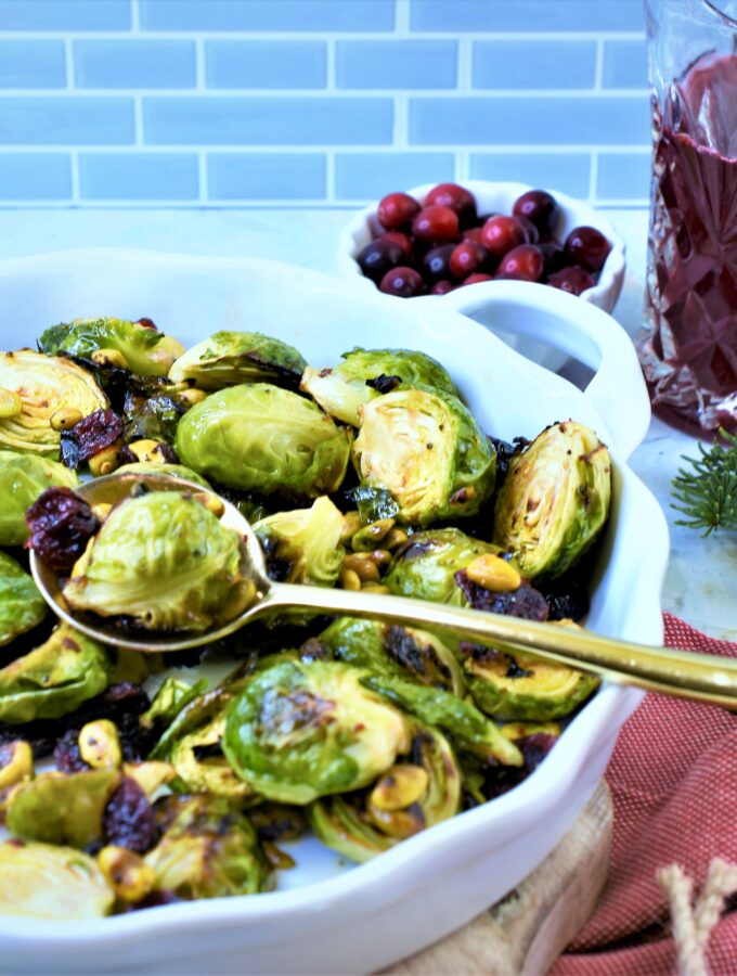 roasted Brussels sprouts with dried cranberries, pistachios and cranberry serrano vinegar in white ceramic side dish